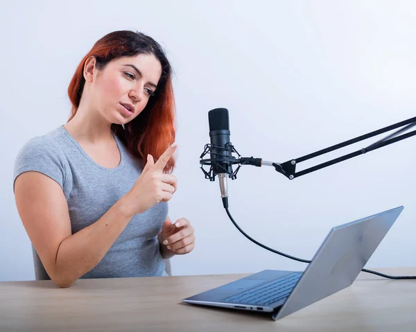 Egy érzelmes nő sugároz a neten egy laptopon. Női rádiós műsorvezető a munkahelyen — Stock Fotó