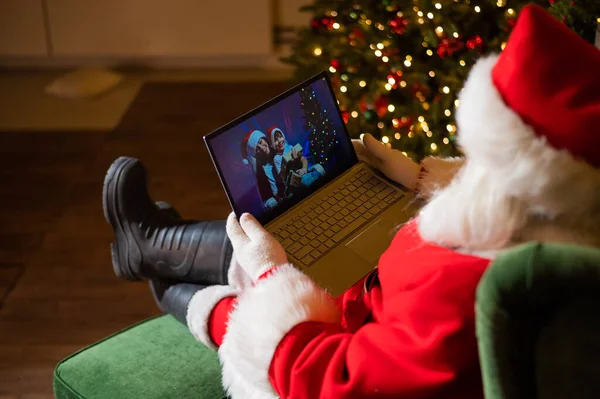 Feliz mamá y su hijo hablando con Santa Claus por chat de vídeo en un ordenador portátil. Mujer y niño desean remotamente Feliz Navidad —  Fotos de Stock