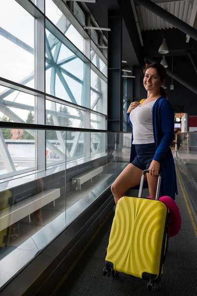 Kaukasierin auf einer waagerechten Rolltreppe mit einem Koffer am Flughafen. Ein Mädchen mit rosa Gepäck fährt auf einem fahrenden Bürgersteig — Stockfoto