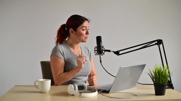 Een charmante vrouw radio host zendt live uit op een laptop. Onlineradioconcept — Stockvideo