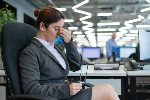 La mujer de negocios toma las manos en el puente de la nariz. Trabajadora de oficina con migraña en el trabajo — Foto de Stock