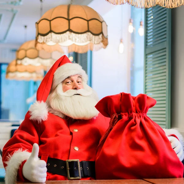 Ο φιλικός Άγιος Βασίλης κάθεται σε ένα καφέ και δείχνει τον αντίχειρά του. Παραμονή Χριστουγέννων — Φωτογραφία Αρχείου