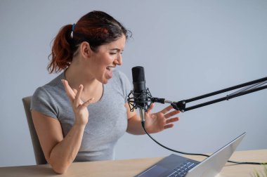 Çekici bir kadın radyo sunucusu dizüstü bilgisayardan canlı yayın yapıyor. Online radyo konsepti
