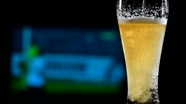 Close-up de cerveja leve espumante fresca em um copo e futebol na TV no fundo. Conceito de bar de esportes — Vídeo de Stock