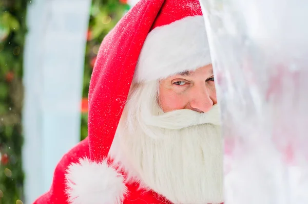 Санта Клаус выглядывает из рождественских украшений на улице — стоковое фото