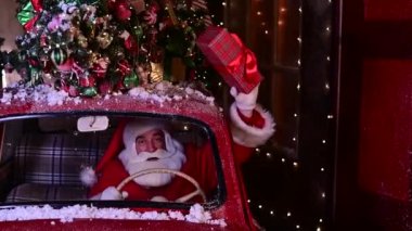 Noel Baba kırmızı bir arabayla hediyeler dağıtır ve pencereden bir hediye kutusu sallar.