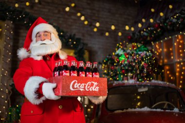 Noel Baba 'nın elinde Coca Cola şişelerinden oluşan bir paket tutarken portresi. Noel tebrik kartı.