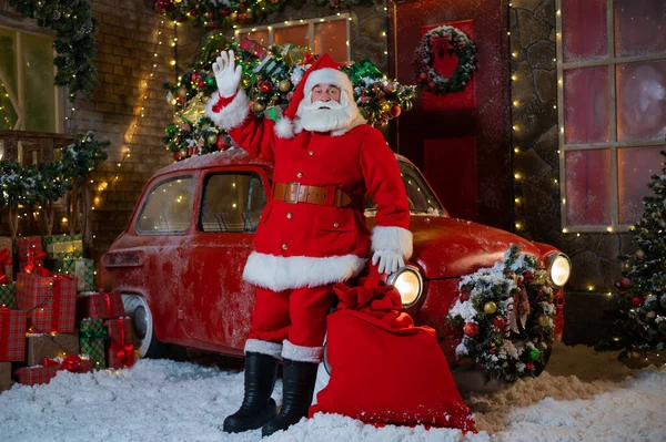 Santa Claus pózuje poblíž červeného klasického auta. Veselé Vánoce — Stock fotografie