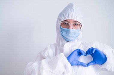 Koruyucu kıyafetli kadın doktor kalbi bir jestle gösteriyor. Hasta sağlığı konsepti