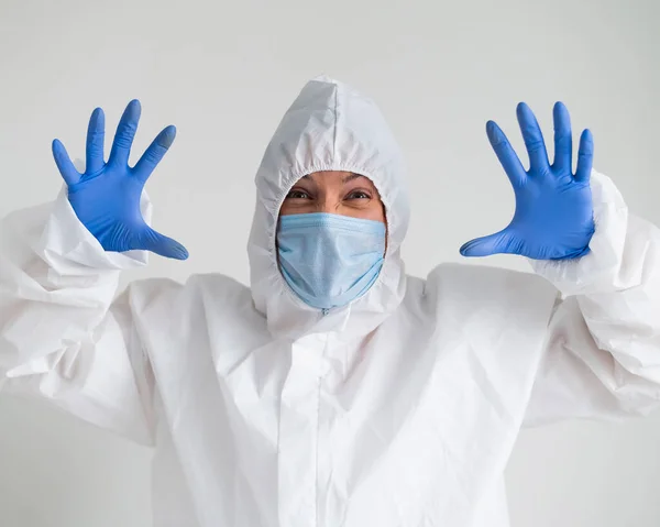 Eine Frau in Schutzanzug und medizinischer Maske mit schrecklicher Fratze. Der Sanitäter hält sich die Handflächen vor das Gesicht und bekommt Angst — Stockfoto