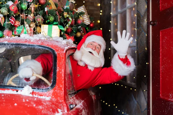 Santa Claus cumprimentando enquanto dirige um carro retro vermelho. Feliz Natal! — Fotografia de Stock