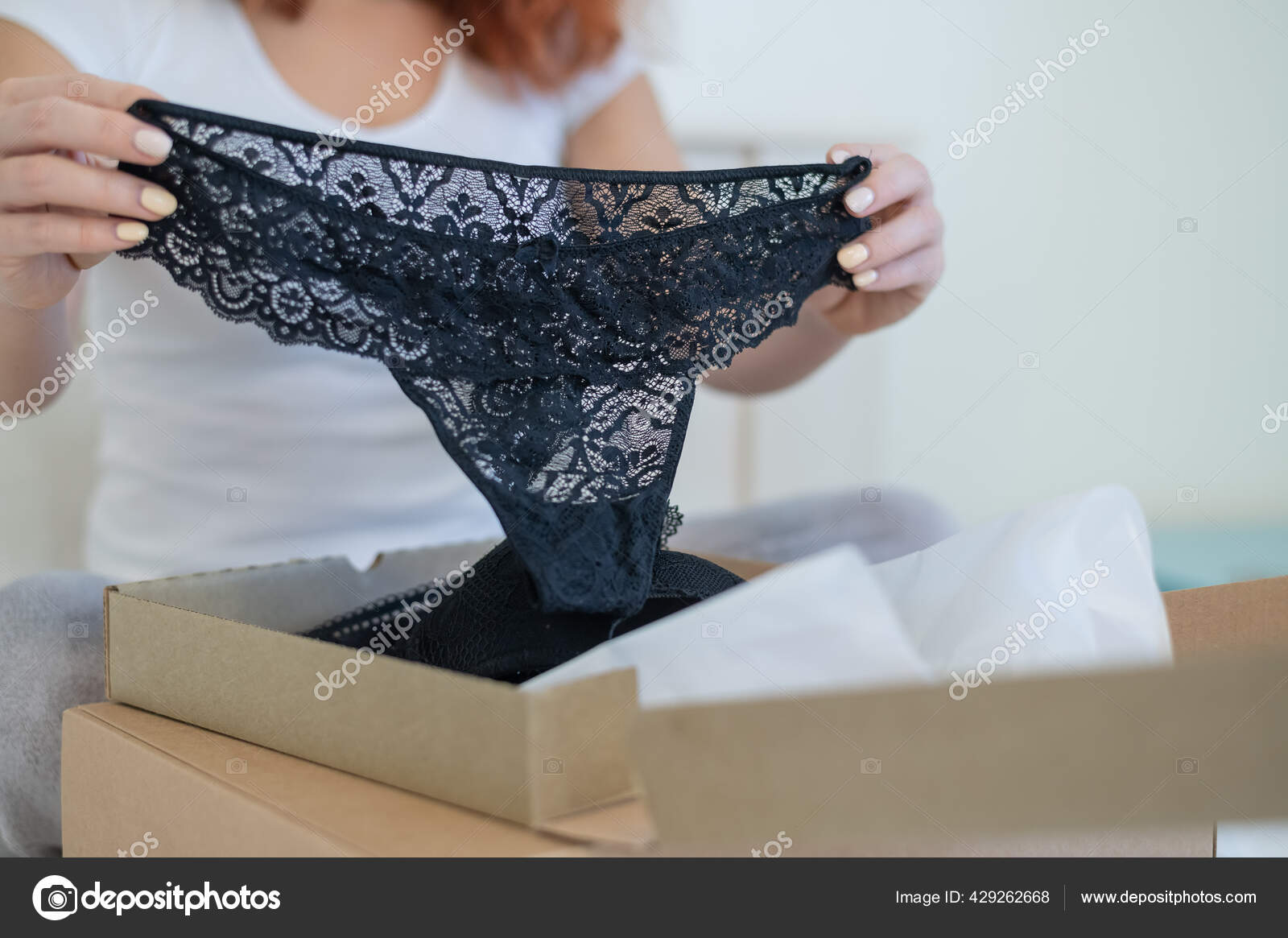 An excited woman unpacks a delivered order. Online shopping for lingerie at  home Stock Photo by ©inside-studio 429262668