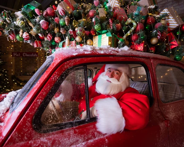 Портрет Санта-Клауса за рулем автомобиля, загруженного елкой и подарками — стоковое фото