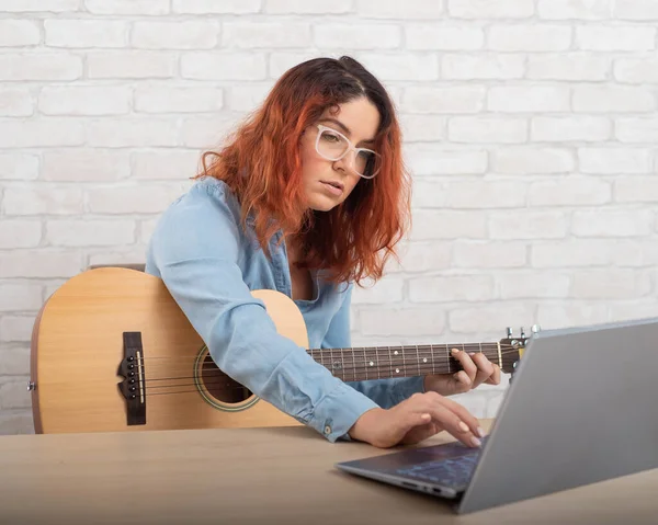 Fehér nő tanul gitározni online. A lány karanténban ül, zenét tanul. — Stock Fotó