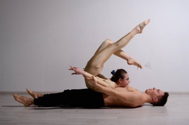 Çift numarası gösteren bir akrobat düeti. Jimnastik yapan bir kadın, gömleksiz bir adamın üstünde amuda kalkarak tulum giyer. Çok esnek sirk sanatçıları..