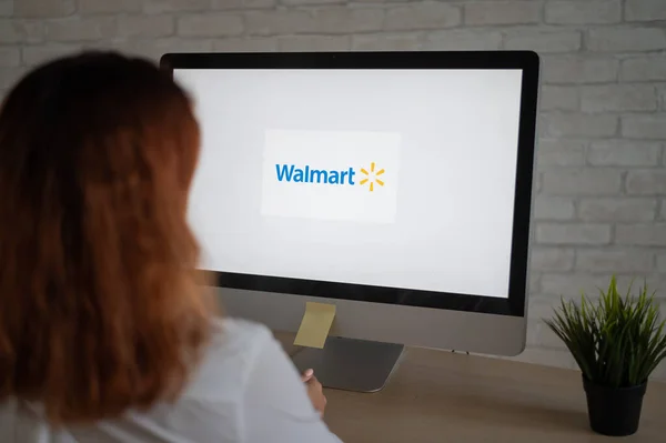 16 de septiembre de 2020 Rusia Novosibirsk: Una mujer se sienta en una computadora con el logotipo de Walmart en la pantalla — Foto de Stock