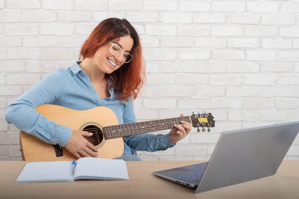 A gyönyörű kaukázusi nő élőben gitározik. Online zenei tréning — Stock Fotó