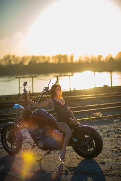 Red-haired woman in sexy lingerie in high heels sits on a motorcycle — Stock Photo, Image