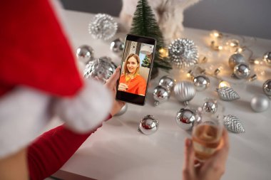Kadınlar cep telefonuyla video görüşmesi yaparlar. Kızlar Noel 'i kutlamak için şampanya içerler ve akıllı telefonla uzaktan iletişim kurarlar.