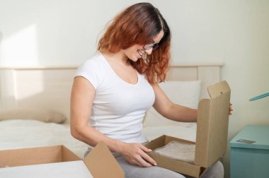 Beyaz bir kadın yatakta otururken sipariş veriyor. Ev teslimatıyla online alışveriş kavramı