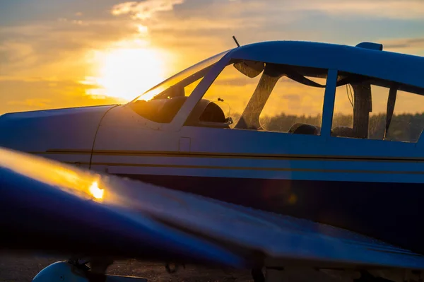 Primer plano de un pequeño avión estacionado con una hélice sobre el telón de fondo de una puesta de sol. — Foto de Stock