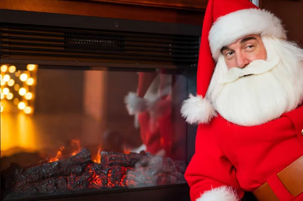 Der Weihnachtsmann sitzt an Heiligabend am Kamin — Stockfoto