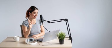 Çekici bir kadın radyo sunucusu dizüstü bilgisayardan canlı yayın yapıyor. Online radyo konsepti. Geniş ekran