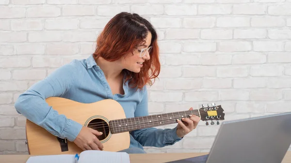 Mooie blanke vrouw speelt de gitaar live. Online muziektraining — Stockfoto