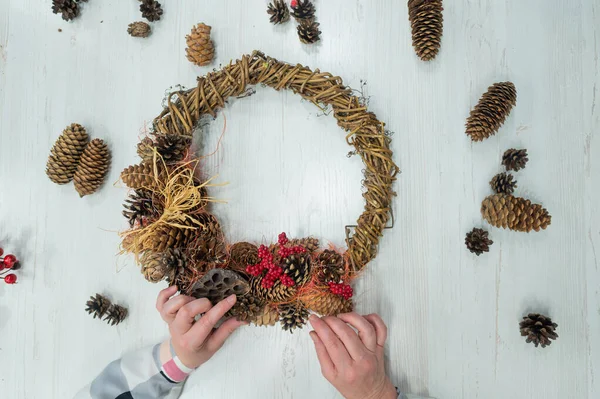 Vista dall'alto di una donna anziana che fa una corona per Natale con le proprie mani. Primo piano delle mani delle donne che fanno decorazioni per il nuovo anno. Fatto a mano — Foto Stock