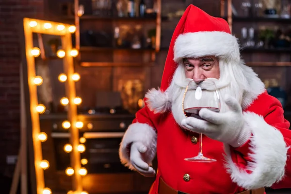 Santa Claus se sklenkou červeného vína přeje veselé Vánoce a říká přípitek — Stock fotografie