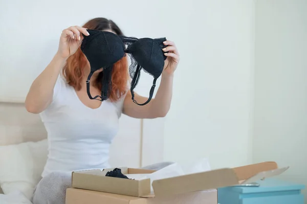 Woman unpacking the purchase of underwear while sitting in bed at home. — Stock Photo, Image