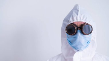 Beyaz arka planda gözlüklü bir maske takan koruyucu kıyafetli bir kadının portresi. Salgın sırasında üniformalı bir kadın doktor..