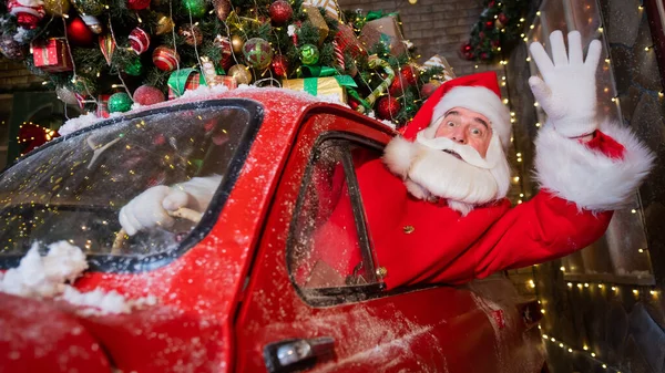 Санта Клаус здоровается за рулём красной ретро-машины. Счастливого Рождества! — стоковое фото