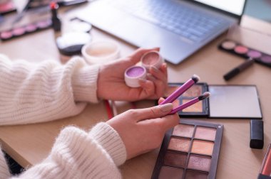 Yüzü olmayan bir kadın dizüstü bilgisayardaki profesyonel bir makyaj sanatçısından online eğitim izliyor. Uzaklık öğrenimi