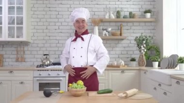 Yaşlı aşçı mutfakta poz veriyor.