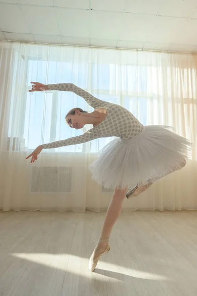 Bellissima ballerina in body e tutù bianco si allena in una classe di danza. Giovane ballerina flessibile posa in scarpe da punta. — Foto Stock