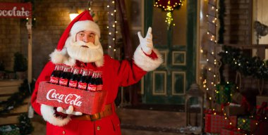 Noel Baba 'nın elinde Coca Cola şişelerinden oluşan bir paket tutarken portresi. Noel tebrik kartı.