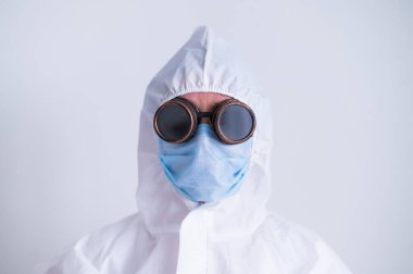 Beyaz arka planda gözlüklü bir maske takan koruyucu kıyafetli bir kadının portresi. Salgın sırasında üniformalı bir kadın doktor..