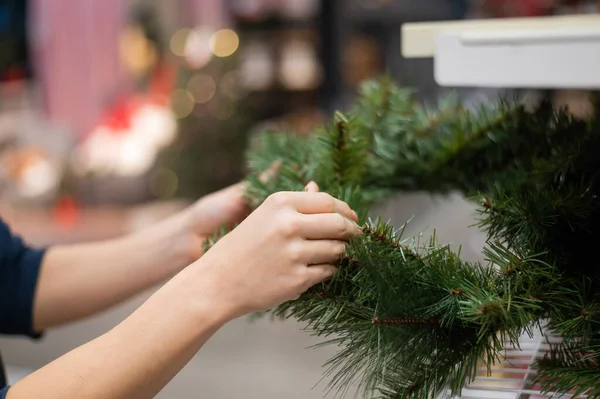 En kvinna köper en julkrans i köpcentret. — Stockfoto