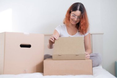 Beyaz bir kadın yatakta otururken sipariş veriyor. Ev teslimatıyla online alışveriş kavramı