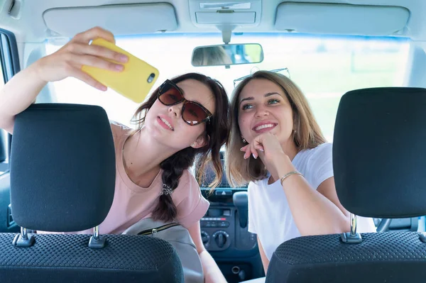 Duas namoradas levam uma selfie no carro. Viagens de carro — Fotografia de Stock
