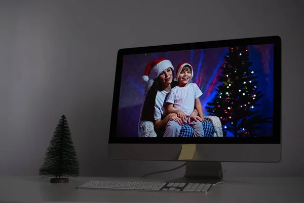 Mãe e filho em chapéus de Papai Noel parabenizar Feliz Natal em uma chamada de vídeo em um computador — Fotografia de Stock