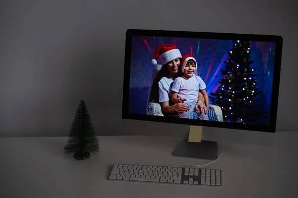 Mãe e filho em chapéus de Papai Noel parabenizar Feliz Natal em uma chamada de vídeo em um computador — Fotografia de Stock