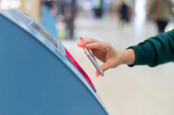 Egy arctalan nő letapogatja a qr kódot az okostelefonjáról. Egy lány önkiszolgáló gépet használ a reptéren, hogy bejelentkezzen repülőjegyekért és kinyomtassa a jegyeket. — Stock Fotó