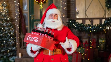 Noel Baba 'nın elinde Coca Cola şişelerinden oluşan bir paket tutarken portresi. Noel tebrik kartı.