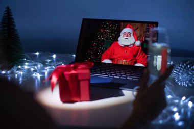 Bilgisayarındaki bir görüntülü aramada Noel Baba 'yla uzaktan konuşan bir kadın. Noel Baba gibi giyinmiş bir adam Noel 'de kız arkadaşını tebrik eder. 2021 Yeni Yıl Konsepti.