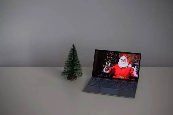Papai Noel deseja Feliz Natal por videochamada em um laptop. Comunicação remota — Fotografia de Stock