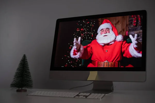 Papai Noel deseja remotamente Feliz Natal através de uma chamada de vídeo no computador. Um homem vestido de Pai Natal num monitor. 2021 conceito de ano novo — Fotografia de Stock