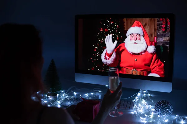 Mulher conversando remotamente com Papai Noel em uma chamada de vídeo no seu computador. Um homem vestido de Papai Noel parabeniza sua namorada no Natal. 2021 conceito de ano novo. — Fotografia de Stock