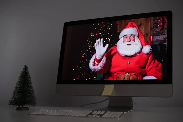 Papai Noel deseja remotamente Feliz Natal através de uma chamada de vídeo no computador. Um homem vestido de Pai Natal num monitor. 2021 conceito de ano novo — Fotografia de Stock